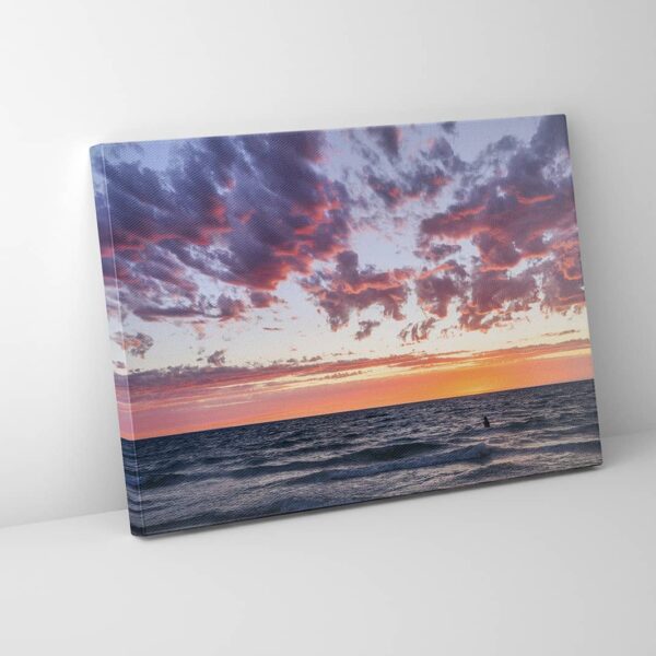 Woman in the ocean watching a pink, purple, orange sunset in Australia